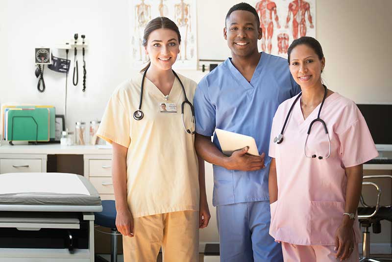 three smiling nurses in different colored scrubs