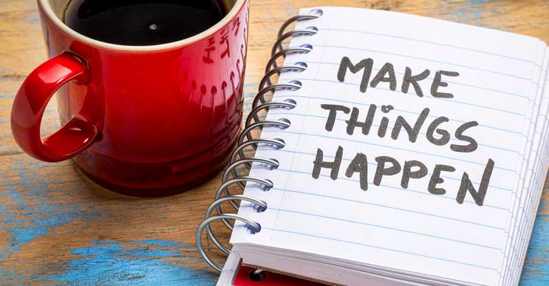 coffee mug sitting next to a note book that says MAKE THINGS HAPPEN